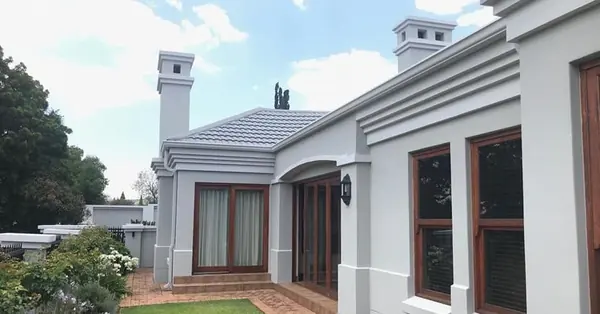 Painting job: grey painted house exterior, brown window frames, blue sky