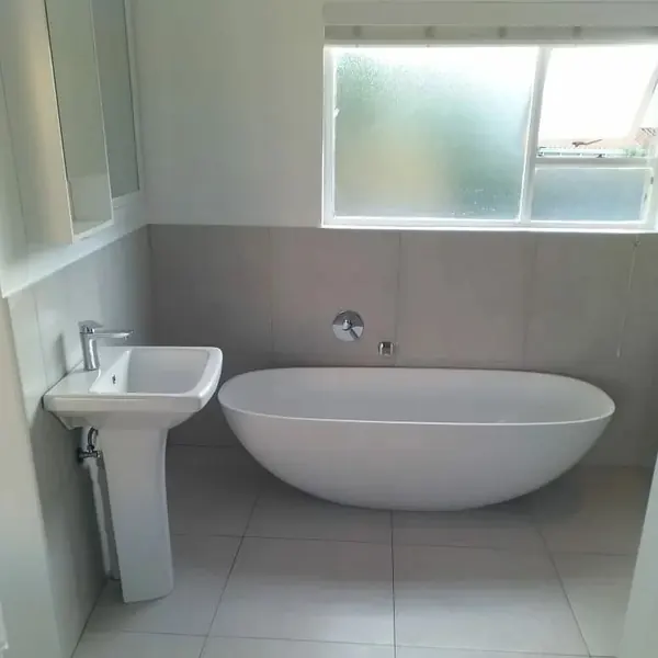 Renovations job: clean bathroom: freestanding bath, pedestal basin, frosted window, tiles