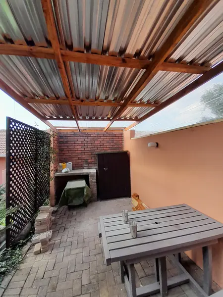 Renovations job: underside of pergola with timber beams and sheets, patio, brick braai