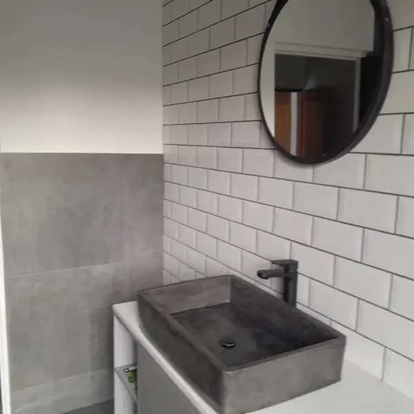 Renovations job: bathroom with concrete basin, round mirror, subway tiles