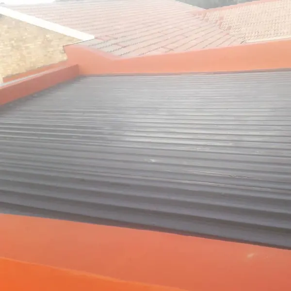 Waterproofing job: roof sheets with orange coating at edges, tiled roof behind