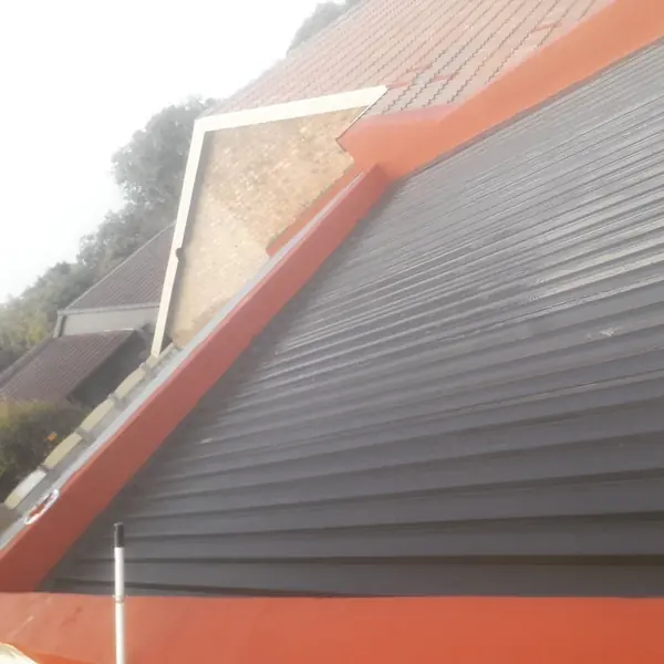 After. Waterproofing job: roof sheets with orange waterproof coating along walls and ridge